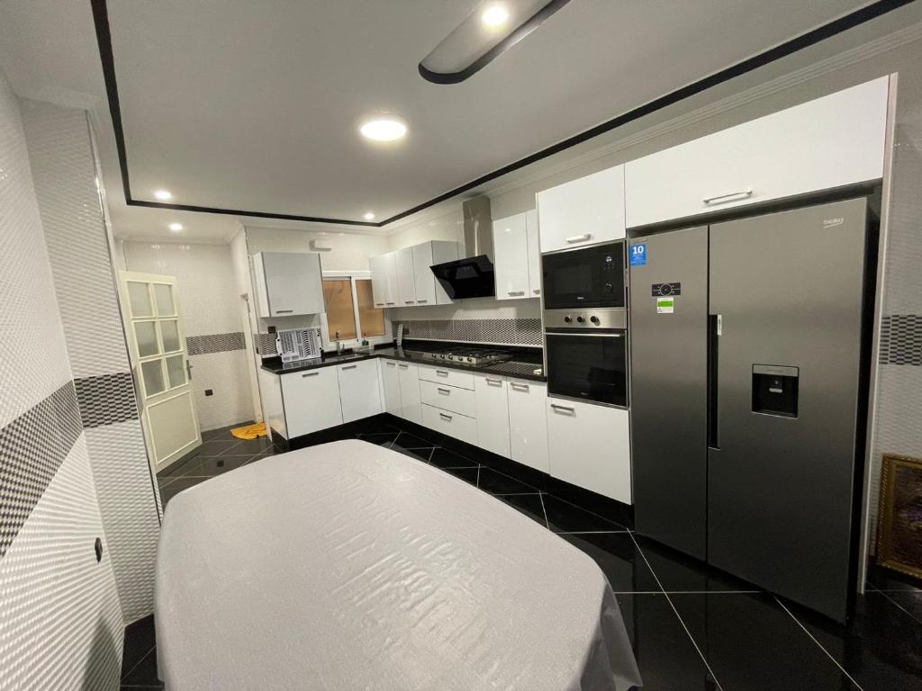 胡塞马Al Hoceima Ajdir Maroc - Maison 5 chambres 10 personnes的厨房配有白色橱柜和黑色冰箱。