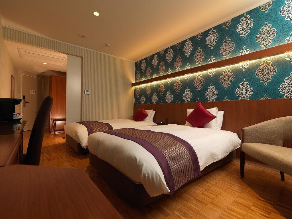 函馆La Jolie Motomachi的酒店客房设有两张床和电视。