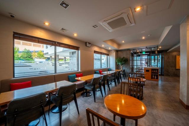 东海市I-check Hyunjin Hotel的餐厅设有桌椅和大窗户。