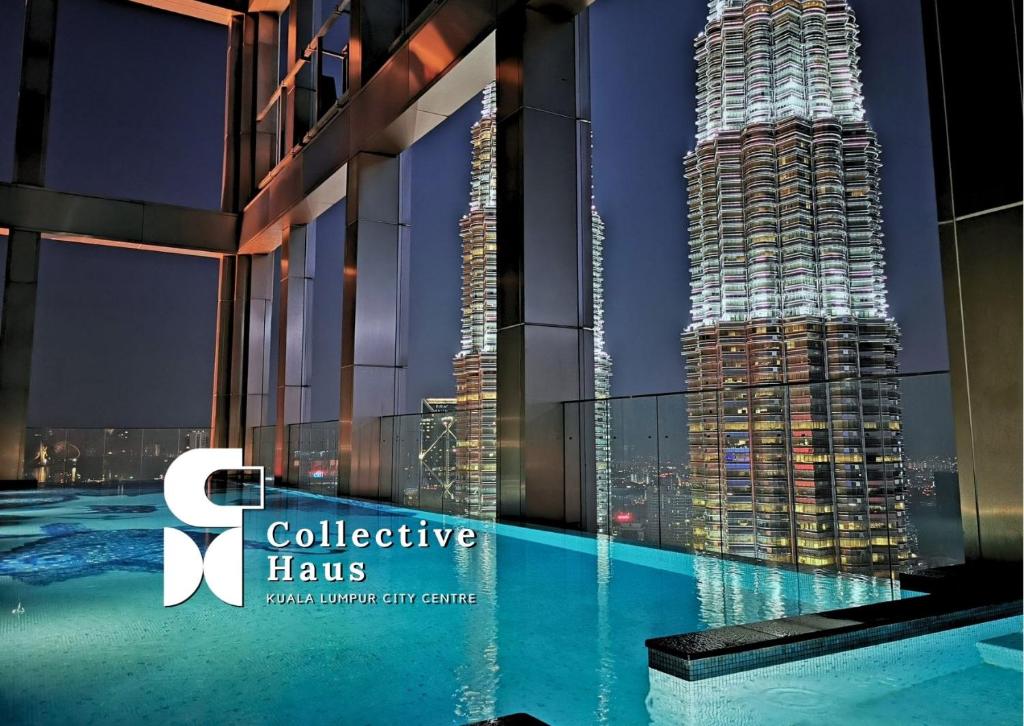 吉隆坡Tropicana Residences Kuala Lumpur by Collective Haus的夜间从游泳池欣赏摩天大楼的景色