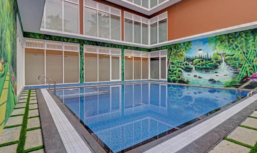 科钦Treebo Trend Golden Terminal Kochi Airport的一座建筑的一侧,设有一座带壁画的游泳池