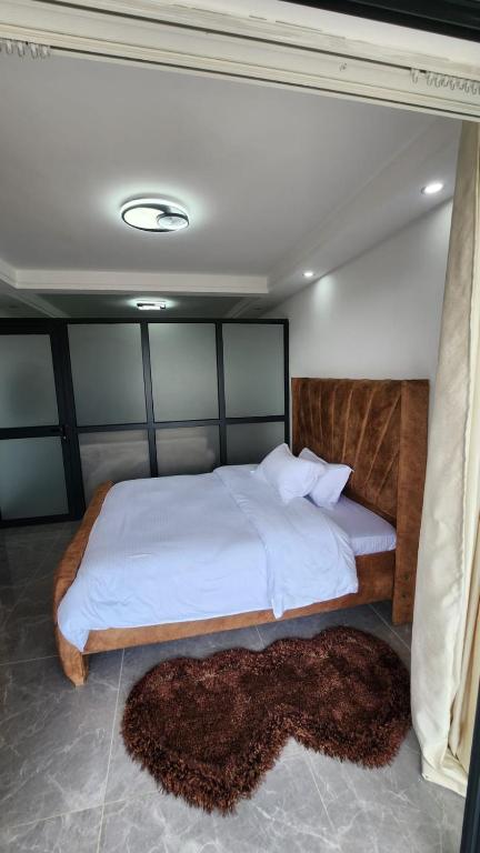 内罗毕Gatundu Heights的一间卧室配有一张带白色床单的大床