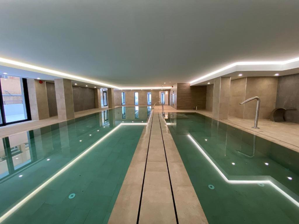 直布罗陀CP Top floor luxury studio with spa and pool的一座大型游泳池,位于一座建筑中,拥有绿色的海水