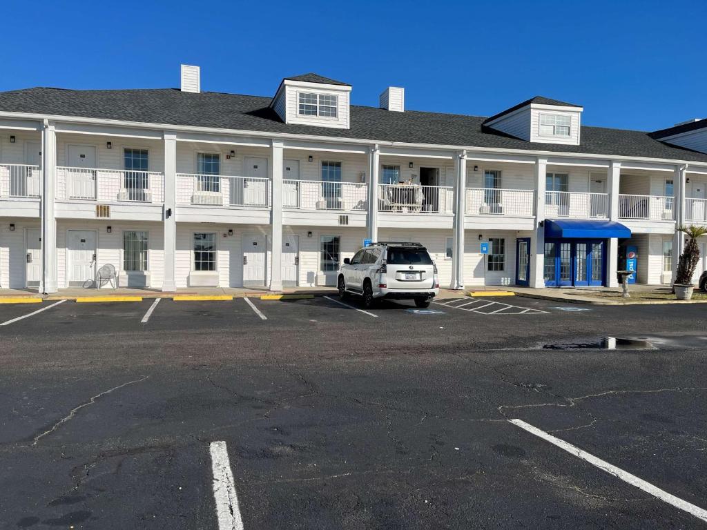 乔治敦Motel 6 Georgetown, SC Marina的停在大楼前停车场的白色汽车