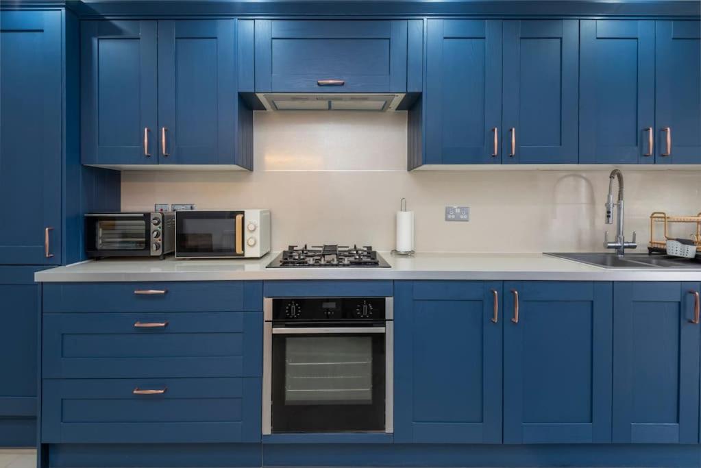 伦敦Stunning 3-Bed House的蓝色的厨房配有蓝色橱柜和微波炉
