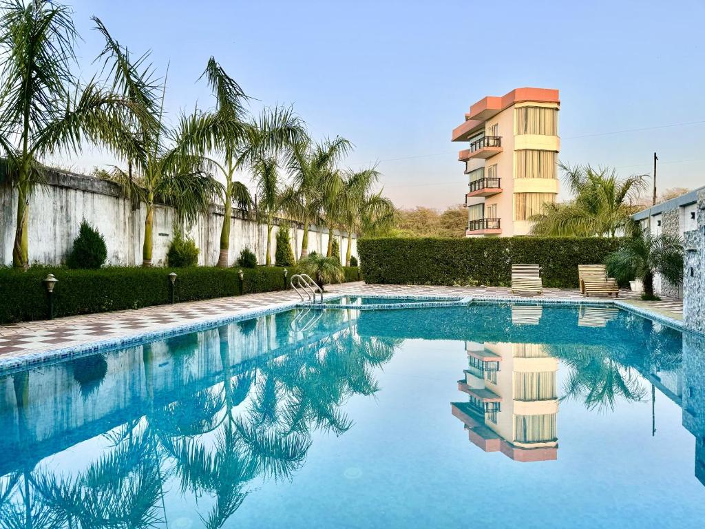 瑞诗凯诗Sumedha Resort & SPA Rishikesh的一座棕榈树游泳池和一座建筑