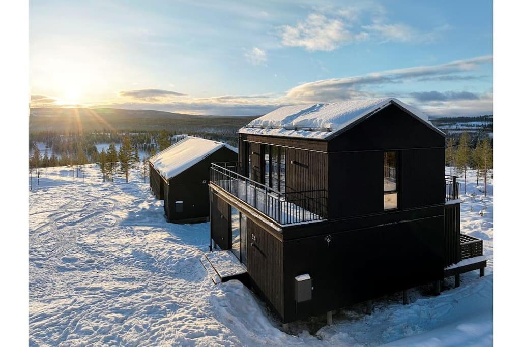 伊德勒The Riverside Mountain Lodge - 110sqm of Calm Luxury的雪中两座小屋,后面是太阳