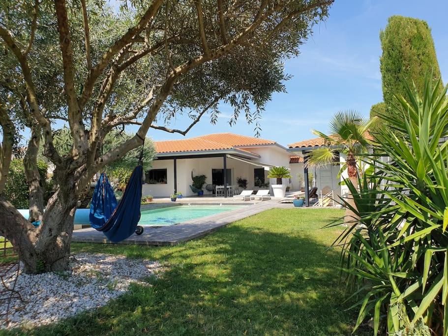 圣让德韦达Belle villa, piscine et cigales au calme !的游泳池旁的房屋,设有1个带吊床的庭院