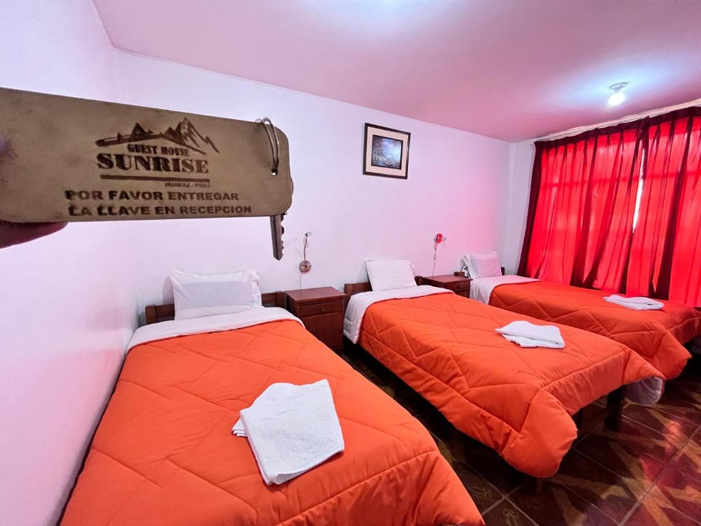 瓦拉斯Sunrise Guest House的配有橙色床单的客房内的三张床