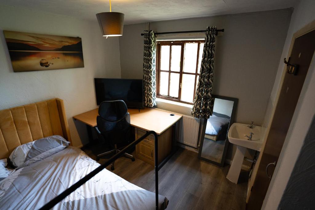 Trimley HeathSevenoaks Guest House的一间卧室配有一张床、一张书桌和一个窗户。