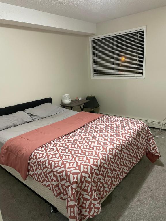 萨斯卡通Ron's Lodge的一间卧室配有一张带红白毯子的床