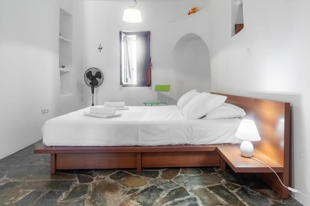 MakrotándalonAegean Cottage Andros的卧室配有一张白色大床和木制床头板