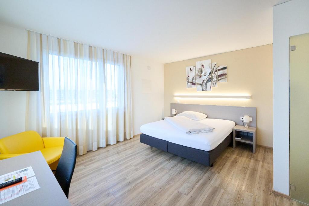 拉亨Hotel am Kreisel Self-Check-In by Smart Hotels的酒店客房配有一张床、一把椅子和一台电视。
