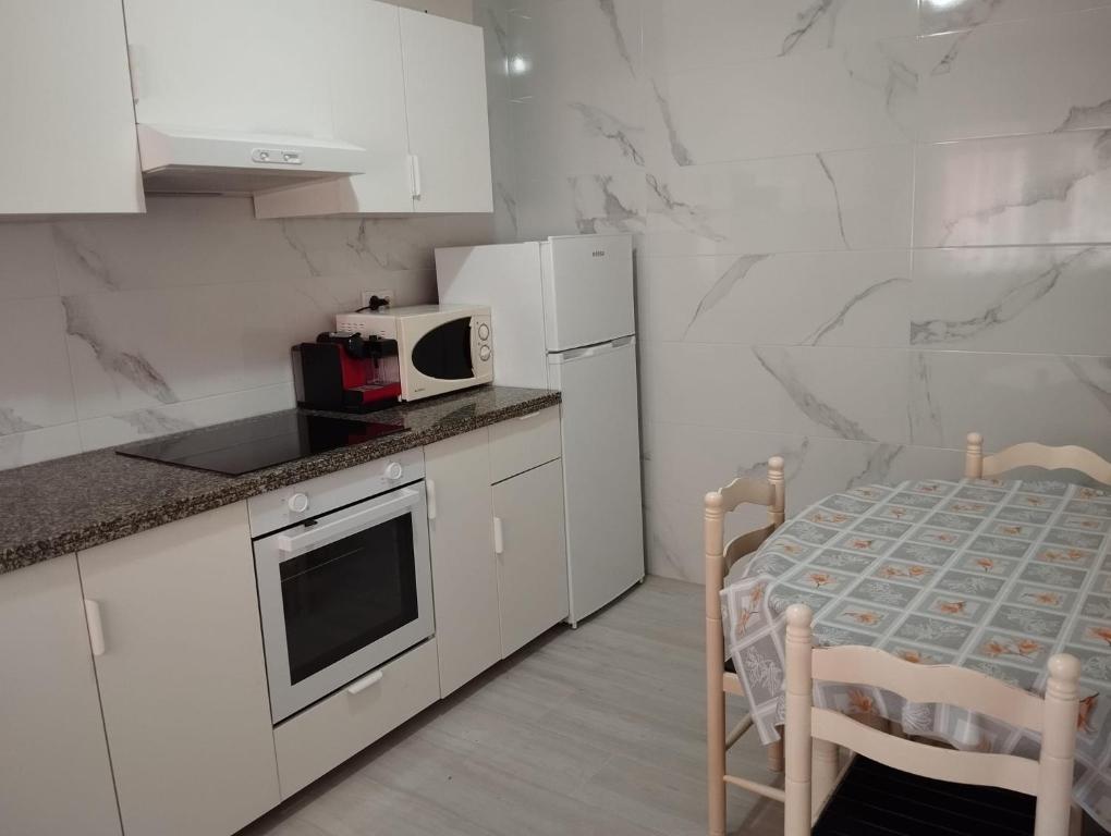 福斯特拉Apartamento céntrico Prado Blanco的白色的厨房配有桌子和微波炉