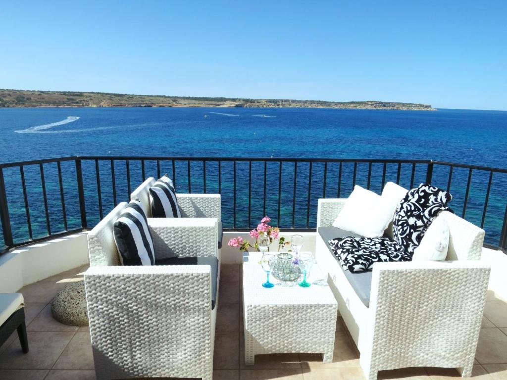 梅利哈Seafront apartment Terrace, lounger & Panoramic ocean views的阳台配有桌椅,享有水景。