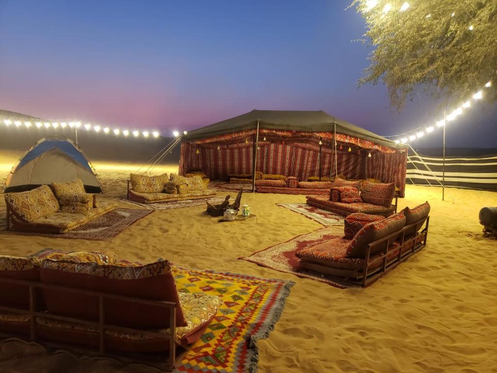 迪拜Overnight Chalet Campsite best for Couples Friends Parties and Overnight Event的沙漠中一个带沙发和椅子的帐篷