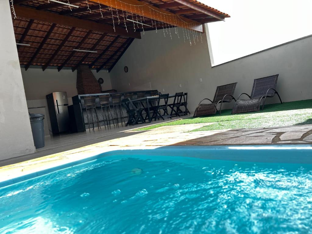 索科罗Chacara em Socorro- SP próx ao centro, com piscina e area gourmet的房屋内带椅子和桌子的游泳池