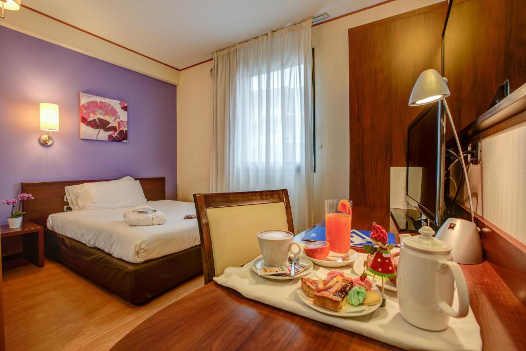 安科纳欧罗巴酒店的酒店客房,配有床和餐桌,上面有食物