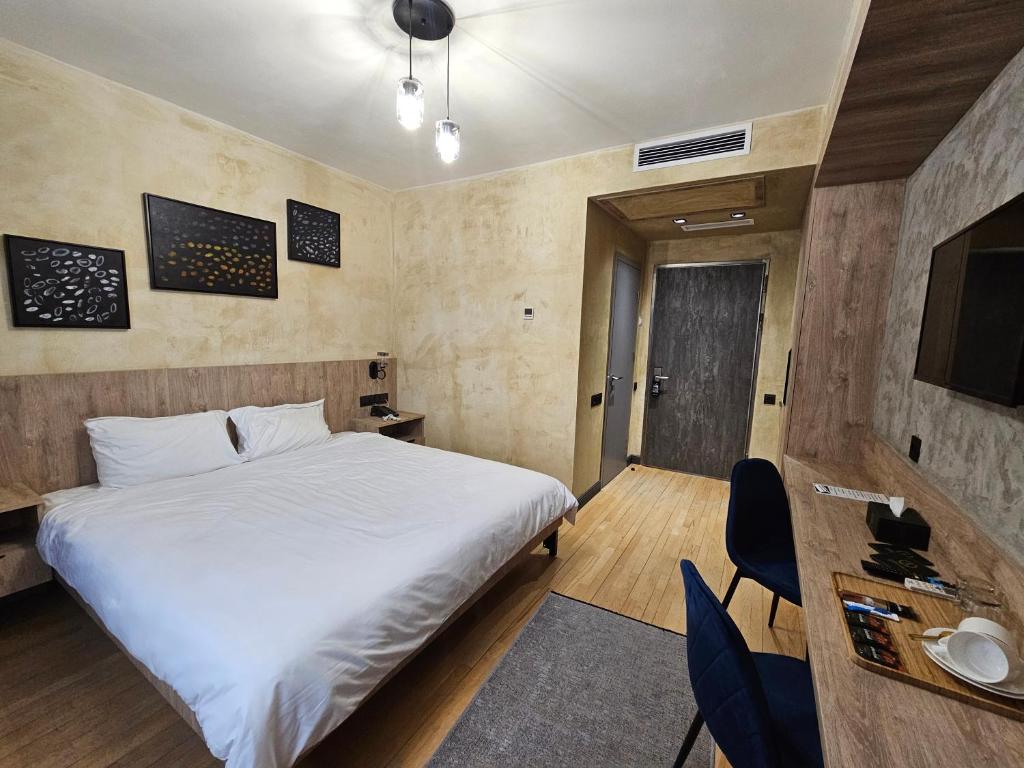 久姆里Aratta Royal Hotel的卧室配有一张白色大床和电视。