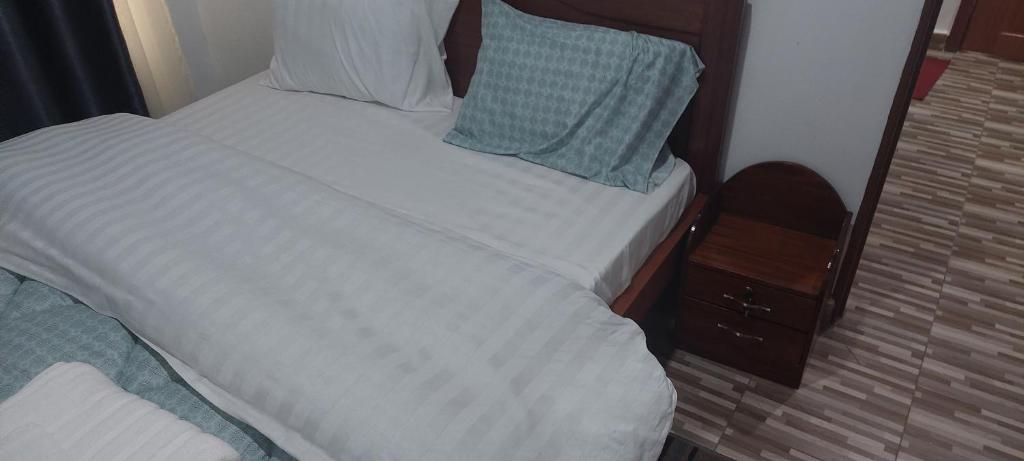 基加利RUbuto ABNB的一张带白色床单和蓝色枕头的床
