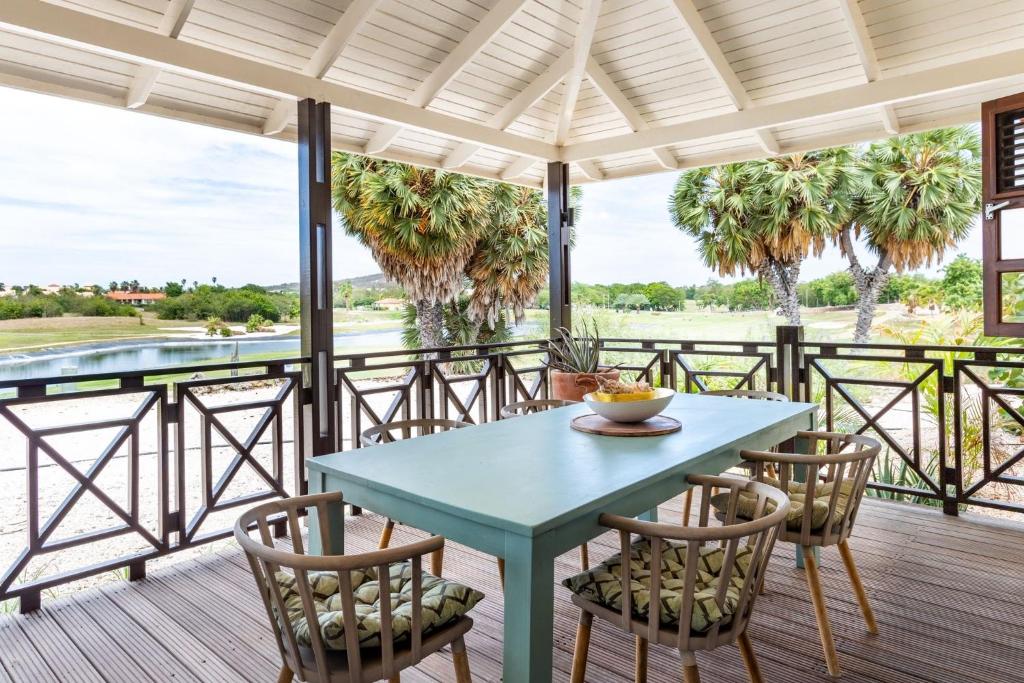 威廉斯塔德Villa at Blue Bay Resort with stunning view的棕榈树甲板上的桌椅