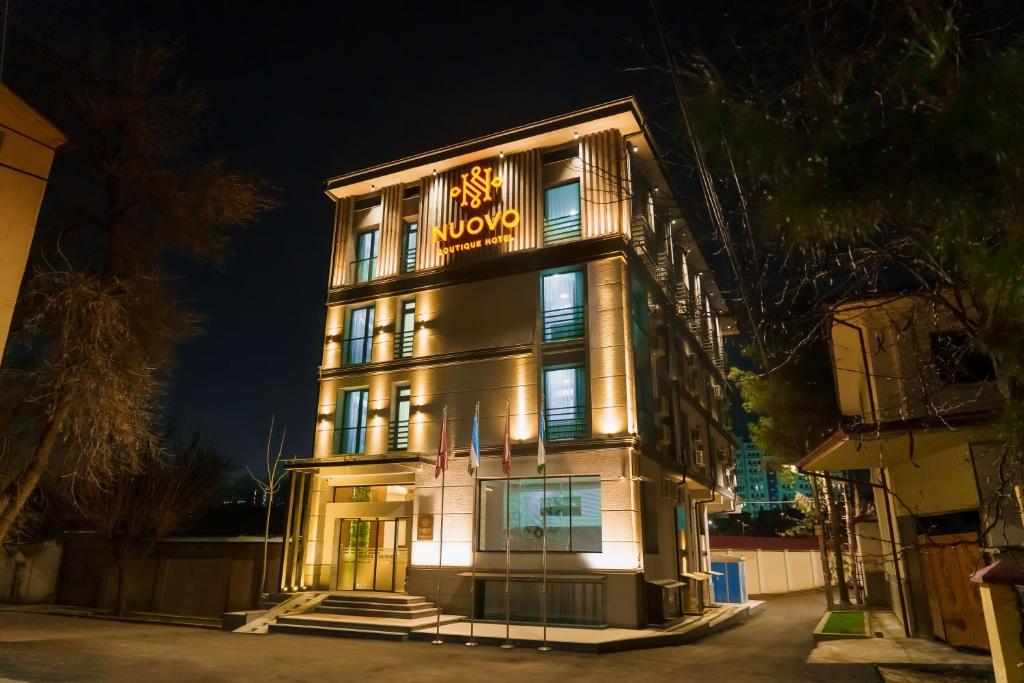 塔什干Nuovo Boutique Hotel的一座晚上有标志的建筑
