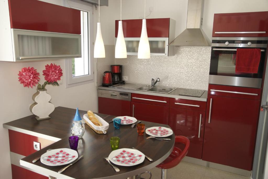 卡尔克富Gîte La Terrasse Du Verger的厨房配有红色橱柜和一张桌子,上面有盘子