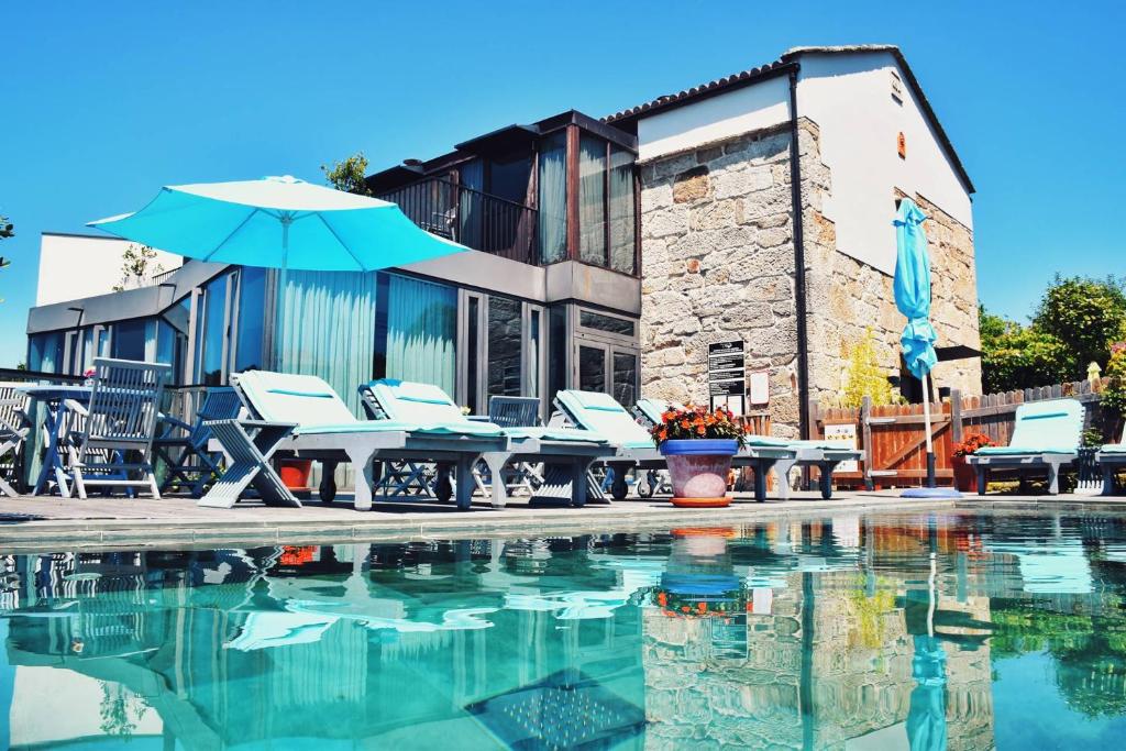 米亚诺Quinta de San Amaro Rias Baixas的一个带桌椅和遮阳伞的游泳池