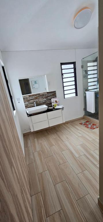 路易港Luxury Villa的一间铺有木地板的白色墙壁浴室