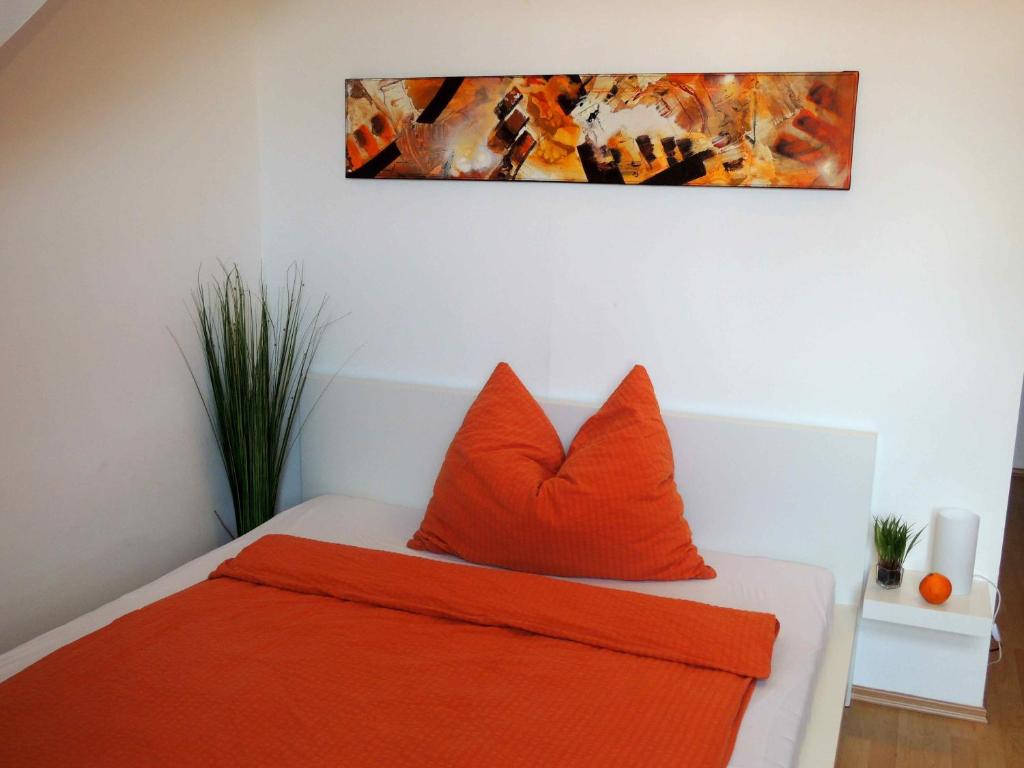 默德林佛伦维拉公寓的卧室配有橙色枕头,墙上挂有绘画作品
