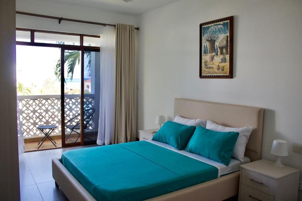 基利菲TAUSI HOMES Sultan Palace Beach Resort的一间卧室配有一张蓝色床单和一个阳台。
