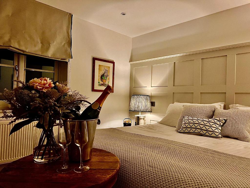 莱奇莱德Five Alls的一间卧室配有一张床,提供一瓶葡萄酒和鲜花