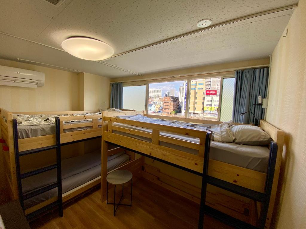 福冈Fukuoka Tabiji Hostel & Guesthouse的客房设有两张双层床和一扇窗户。