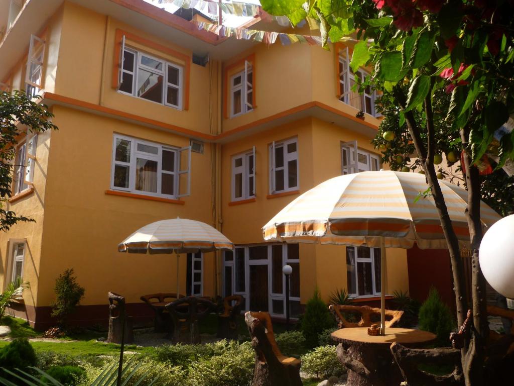 加德满都安第斯之家旅舍的前面有桌子和遮阳伞的黄色建筑
