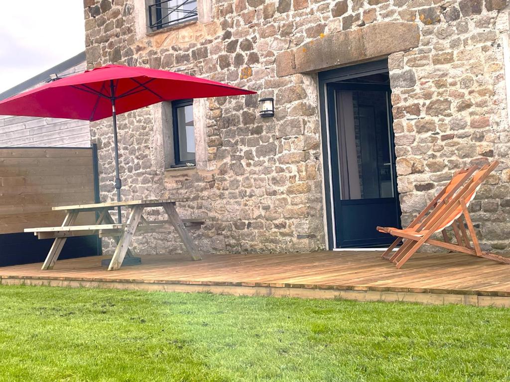 蒙特多尔Cottage Le Phare - Le Clos de la Morière的木甲板上的野餐桌和红伞
