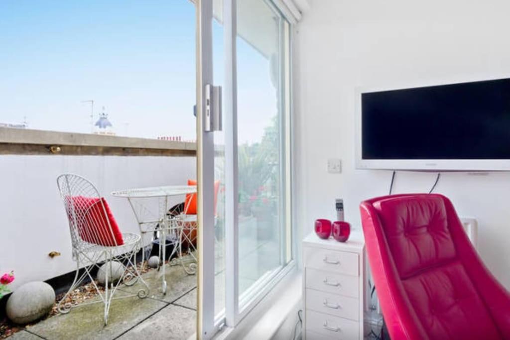 伦敦Zone 1! 2 bed duplex Apartment!的一间带电视和红色椅子的客厅