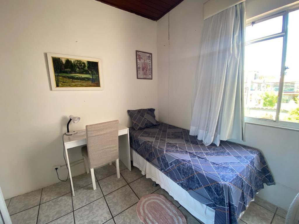 萨尔瓦多Quarto em stella maris的一间卧室配有一张床、一张书桌和一个窗户。