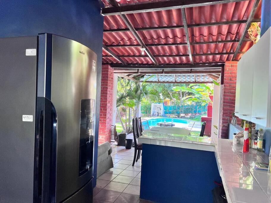 拉利伯塔德Casa en Condominios San Blas 5 minutos del Tunco的厨房配有不锈钢冰箱和游泳池