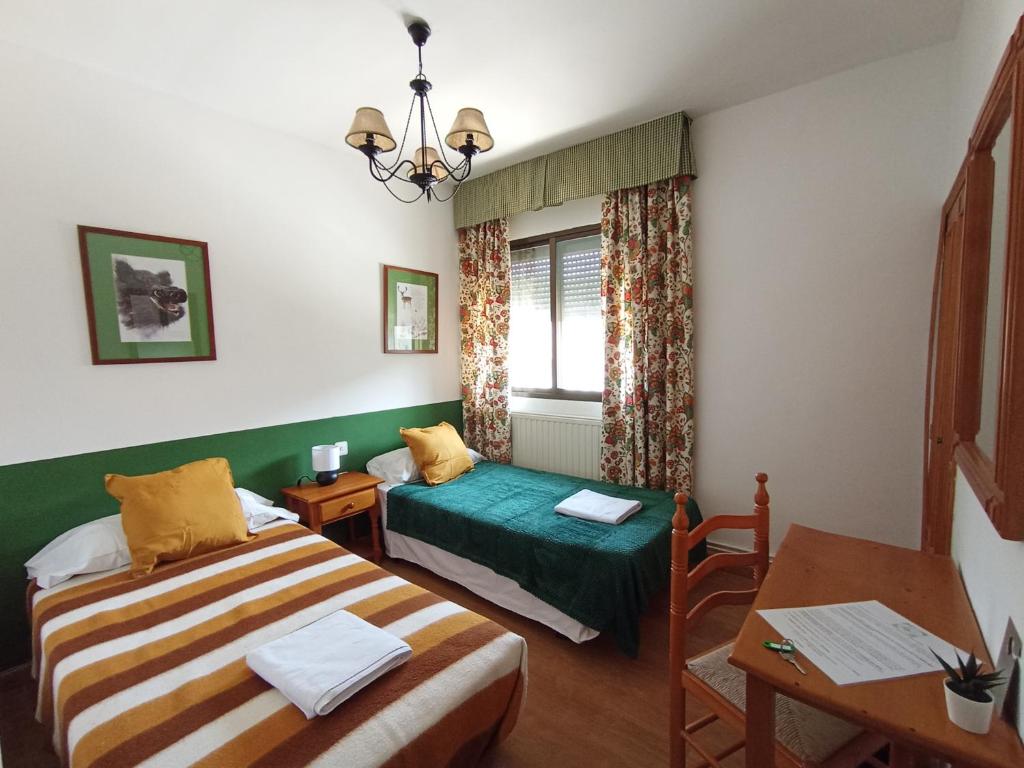 Poveda de la SierraHOSTAL RURAL ALTO TAJO POVEDA的客房设有两张床、一张桌子和一扇窗户。