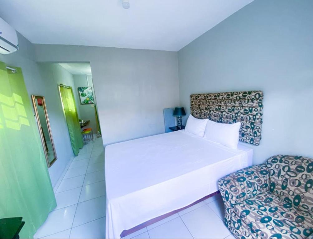 蒙特哥贝Jobs Inn Jamaica的白色卧室配有床和椅子