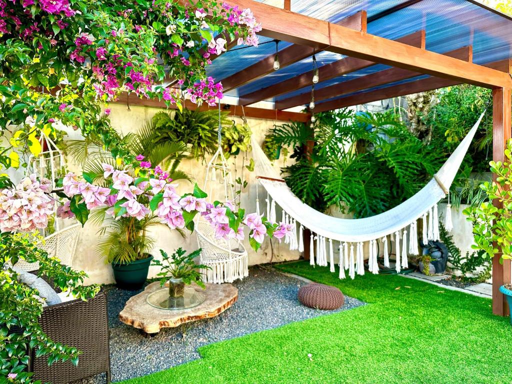 阿拉胡埃拉Airport Traveler's home.的花园里的吊床,种有鲜花和植物