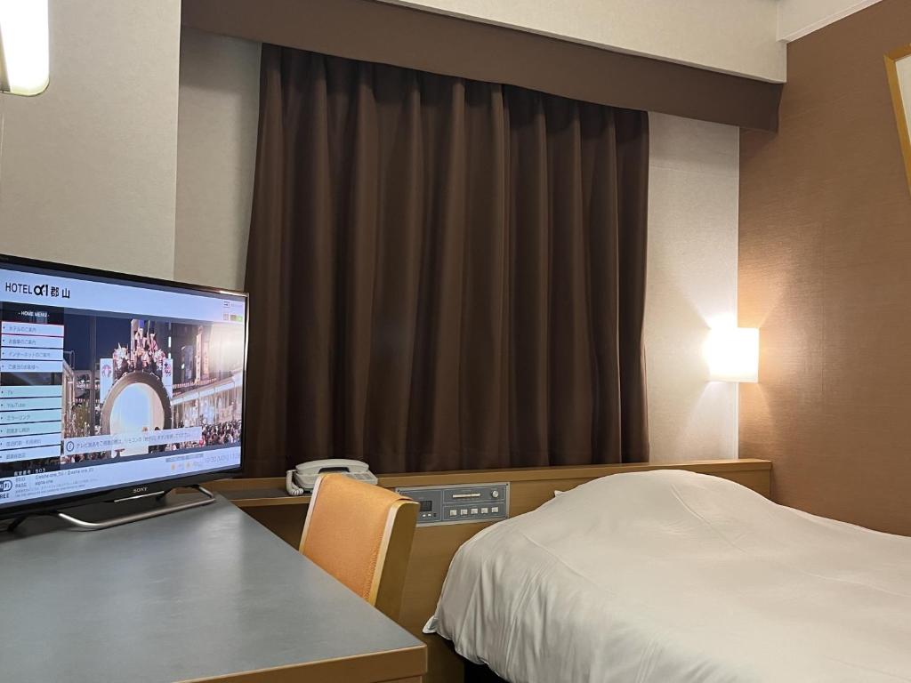 郡山Hotel Alpha-One Koriyama的配有一张床和一台平面电视的酒店客房