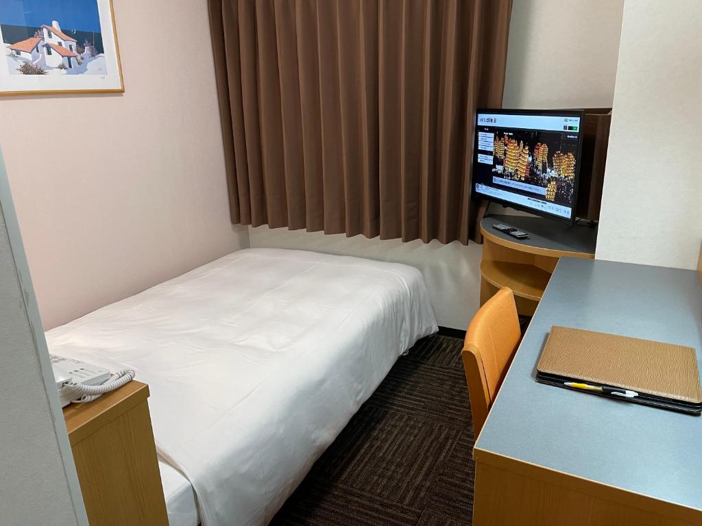 秋田Hotel Alpha-One Akita的酒店客房配有一张床、一张书桌和一台电视。