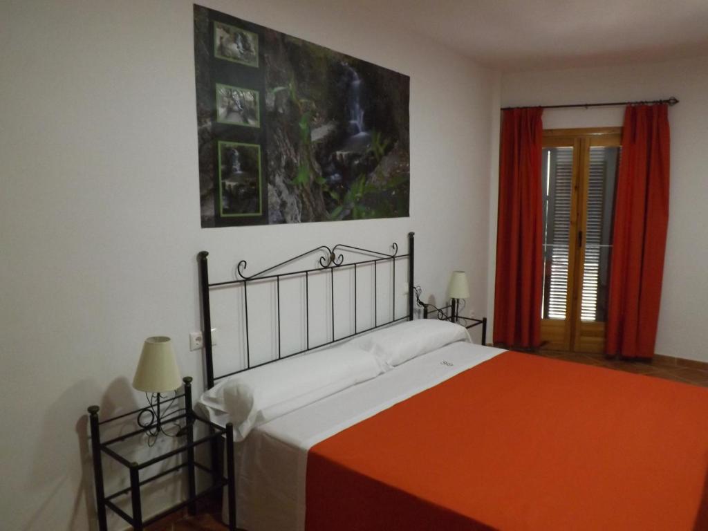 BeiresCasa Rural ENTRESIERRAS的一间卧室配有一张带橙色毯子的床