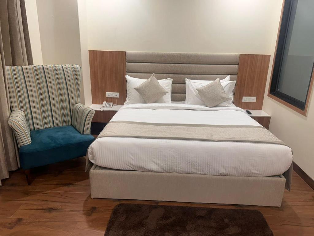 斋浦尔Cilantro Comfort Jaipur的一间卧室配有一张大床和一张蓝色椅子
