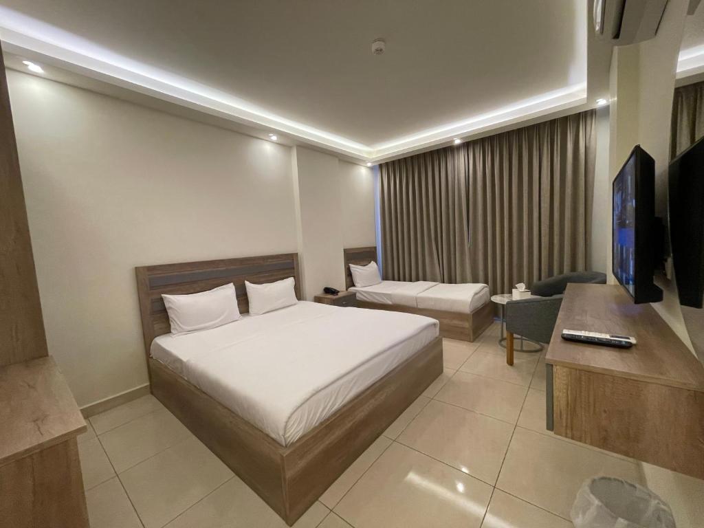 亚喀巴Aster Hotel Aqaba的酒店客房配有床、沙发和电视。