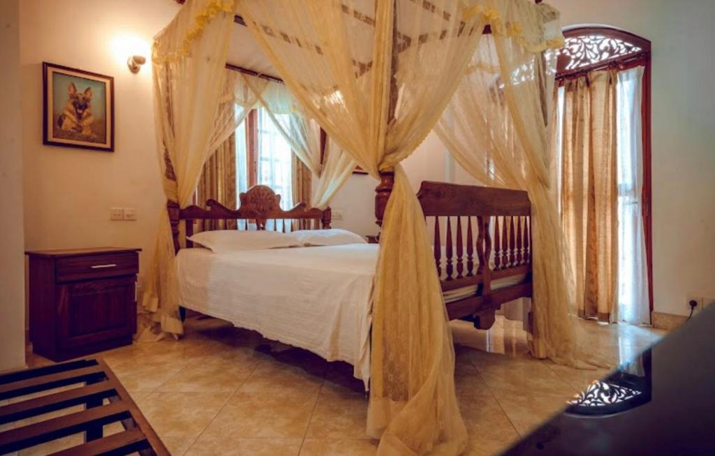 尼甘布Village Inn Resort的一间卧室配有带窗帘的天蓬床