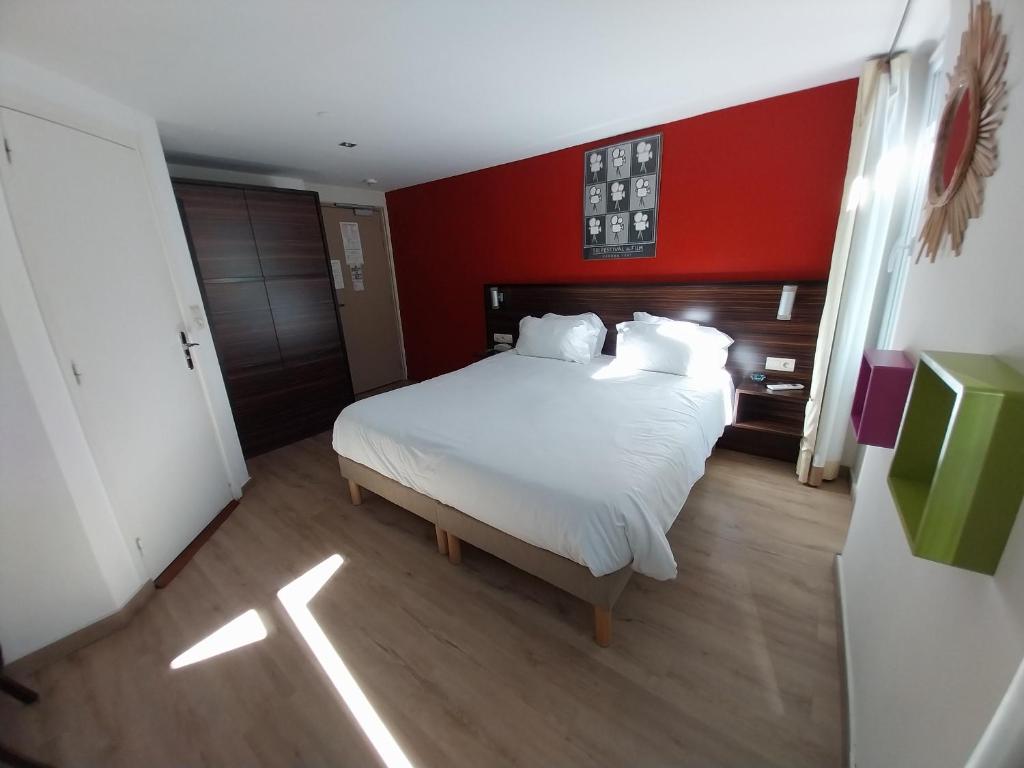 戛纳米斯特拉尔酒店的卧室配有白色的床铺和红色的墙壁