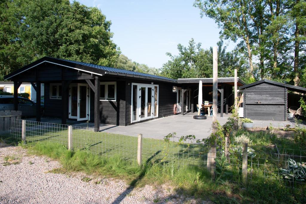 MatslootLuxe en ruim chalet met airco bij Leekstermeer的黑色房子,设有门廊和院子