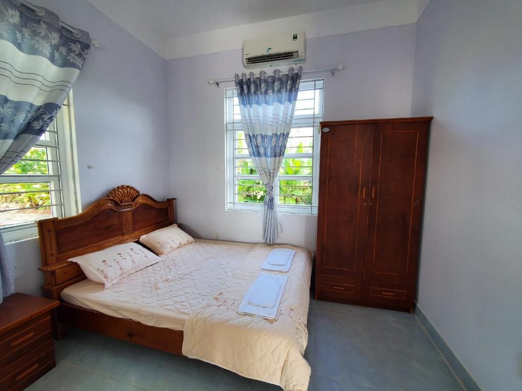 Xóm MũiVườn Quốc Gia U Minh Hạ的一间卧室配有一张床、一个梳妆台和两个窗户。